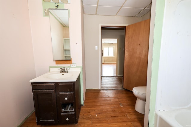 bathroom featuring vanity, hardwood / wood-style flooring, toilet, and a drop ceiling