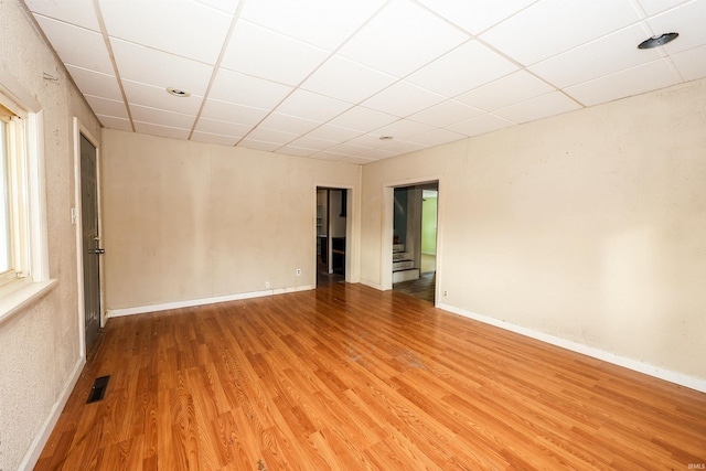 empty room with hardwood / wood-style flooring and a drop ceiling