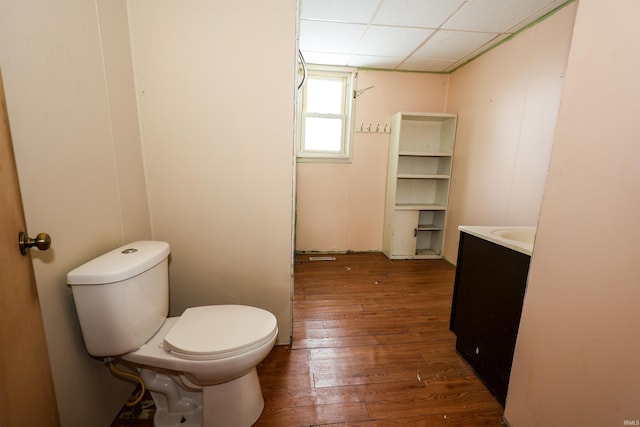 bathroom featuring hardwood / wood-style flooring, a drop ceiling, toilet, and vanity