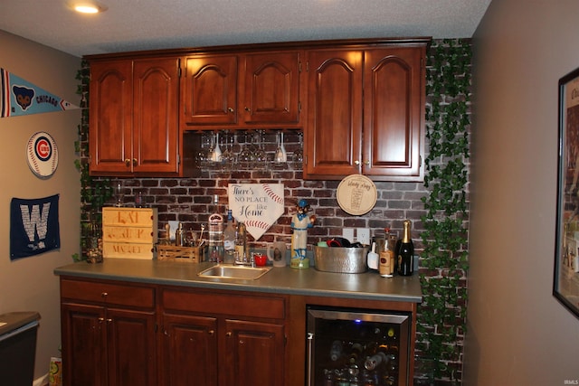 bar featuring a textured ceiling, beverage cooler, and sink