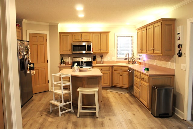 kitchen featuring a breakfast bar, sink, light hardwood / wood-style flooring, a kitchen island, and stainless steel appliances