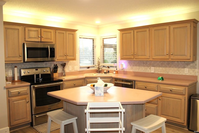 kitchen with a center island, a kitchen bar, sink, and appliances with stainless steel finishes