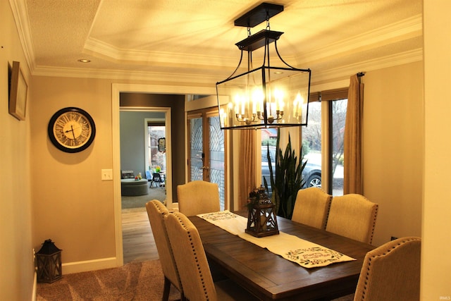 carpeted dining area with french doors, a raised ceiling, ornamental molding, a textured ceiling, and a chandelier