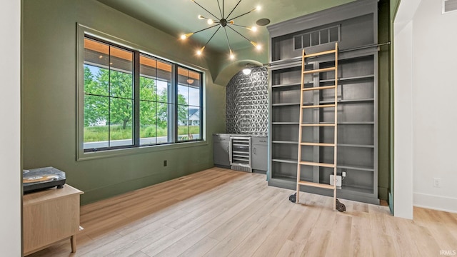 interior space featuring light hardwood / wood-style floors, wine cooler, and a notable chandelier