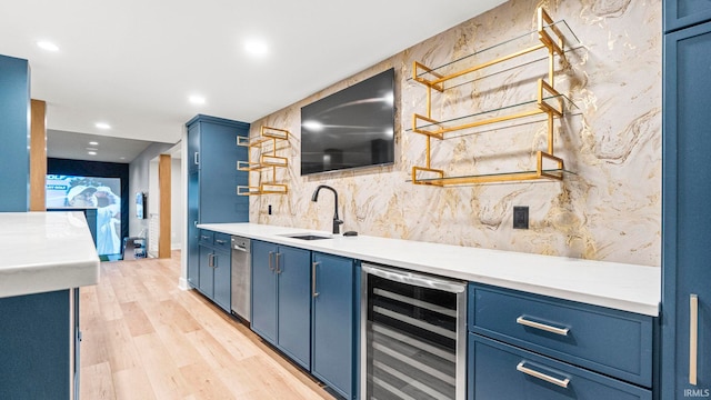 kitchen featuring blue cabinetry, sink, beverage cooler, and light hardwood / wood-style flooring