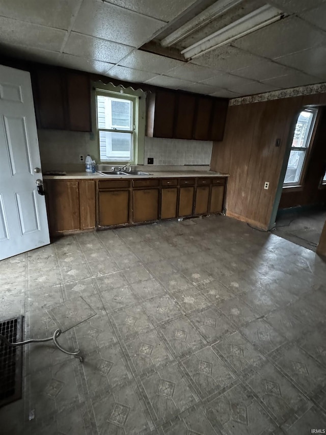 kitchen with a paneled ceiling, wooden walls, and sink