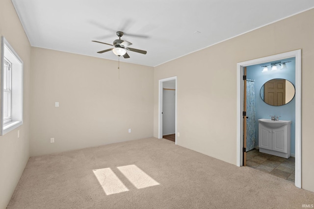 unfurnished bedroom featuring carpet floors, ensuite bathroom, and ceiling fan