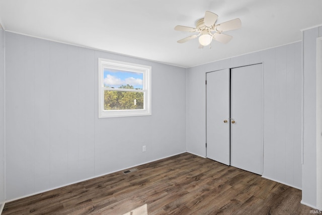 unfurnished bedroom featuring dark hardwood / wood-style flooring, a closet, and ceiling fan