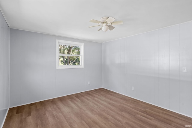 spare room featuring hardwood / wood-style floors, ceiling fan, and wood walls