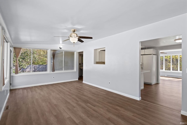 unfurnished room featuring dark hardwood / wood-style floors, baseboard heating, and ceiling fan