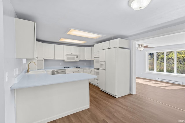 kitchen featuring sink, a baseboard radiator, kitchen peninsula, white appliances, and white cabinets