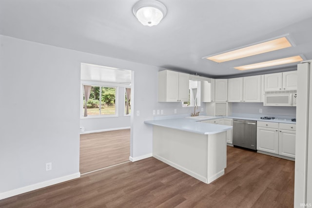 kitchen featuring kitchen peninsula, sink, white cabinets, and white appliances