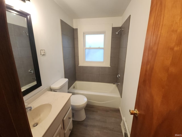 full bathroom with hardwood / wood-style floors, vanity, tiled shower / bath combo, and toilet