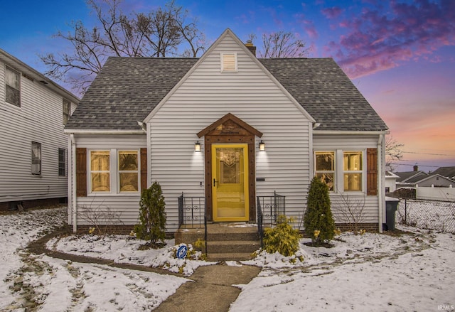 view of front of house featuring a shingled roof, a chimney, and fence