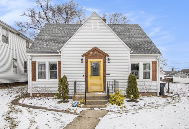 view of front of house with a shingled roof, a chimney, and fence