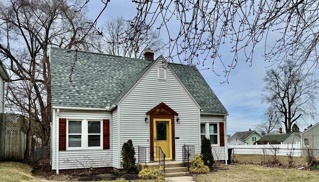 view of front of property with roof with shingles, fence, and a chimney