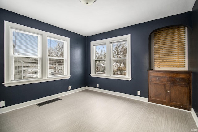 empty room featuring light wood-type flooring, visible vents, and baseboards