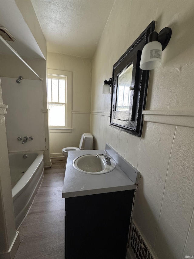 full bathroom featuring bathing tub / shower combination, a textured ceiling, toilet, vanity, and hardwood / wood-style flooring