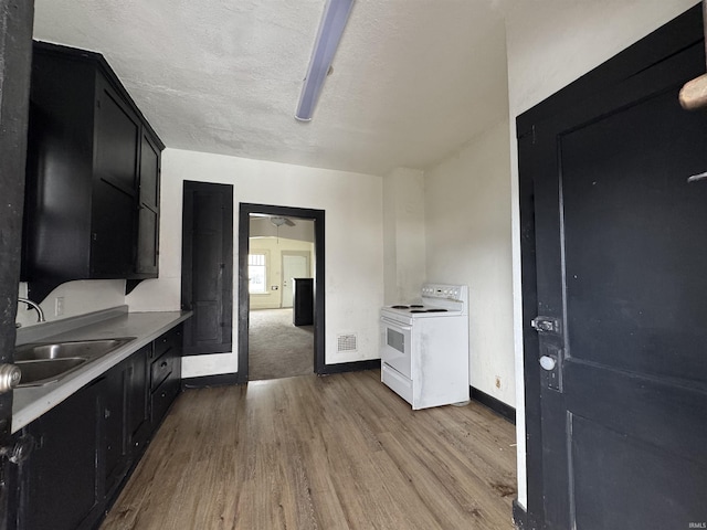 kitchen featuring light wood-type flooring, a textured ceiling, ceiling fan, sink, and electric stove