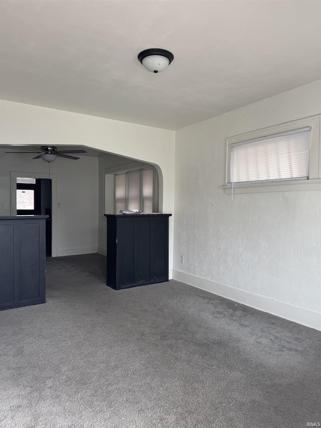 unfurnished living room with ceiling fan and dark carpet