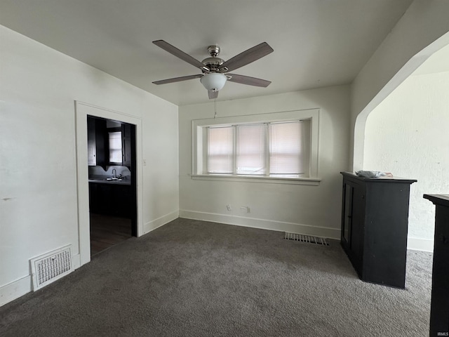 unfurnished bedroom with ceiling fan, sink, and dark carpet