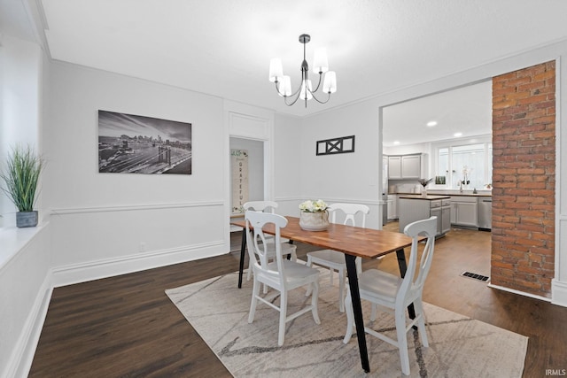 dining area featuring ornate columns, crown molding, hardwood / wood-style floors, and an inviting chandelier