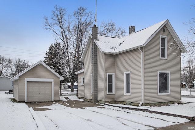 snow covered property featuring a garage and an outdoor structure