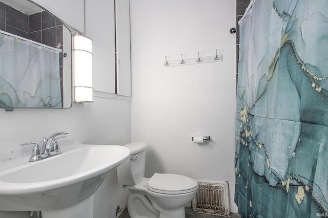 bathroom featuring a shower with curtain, toilet, and sink