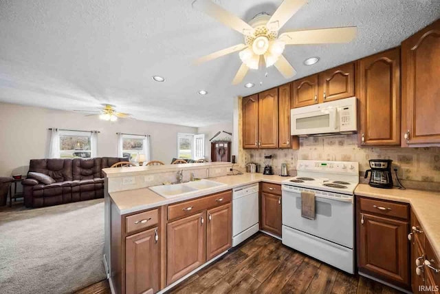 kitchen with sink, white appliances, dark hardwood / wood-style flooring, kitchen peninsula, and ceiling fan