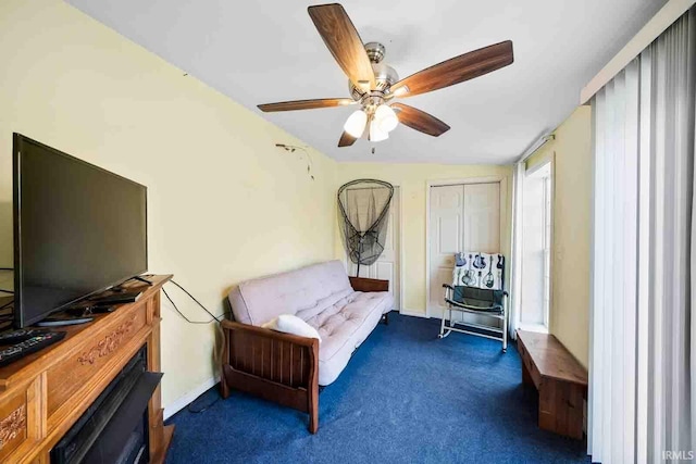 living area with ceiling fan and dark carpet