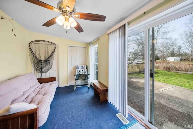 living area featuring ceiling fan and dark carpet