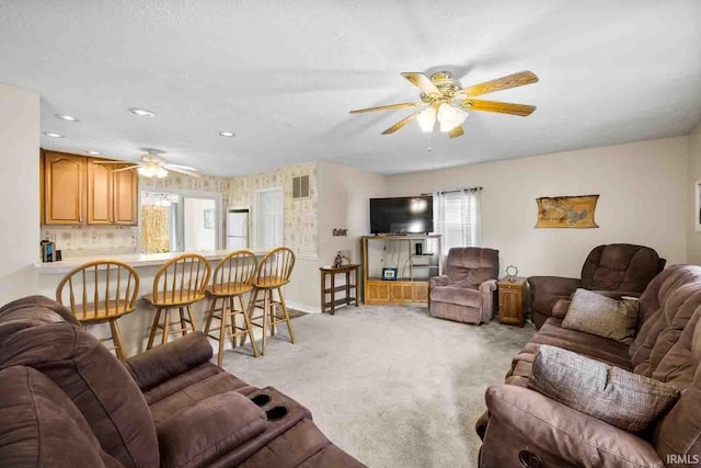 living room with ceiling fan, light colored carpet, a textured ceiling, and a wealth of natural light