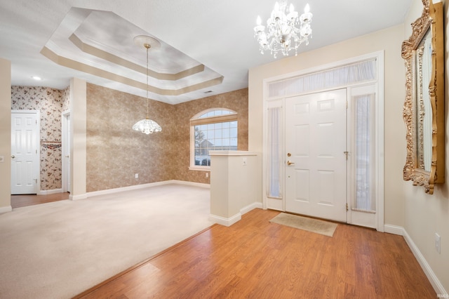 foyer featuring hardwood / wood-style flooring, a raised ceiling, crown molding, and an inviting chandelier