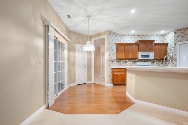 kitchen featuring sink, hanging light fixtures, an inviting chandelier, light hardwood / wood-style flooring, and stove