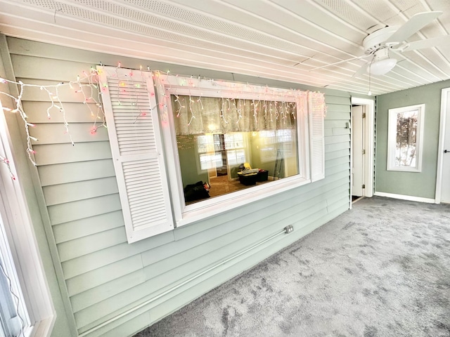 interior details with ceiling fan, carpet, and wood walls