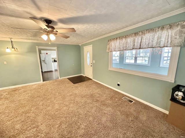 spare room with a textured ceiling, dark carpet, ceiling fan, and crown molding