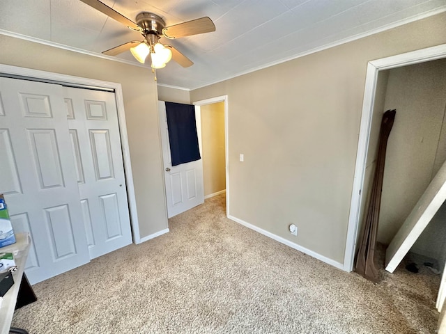 unfurnished bedroom featuring ceiling fan, light colored carpet, crown molding, and a closet