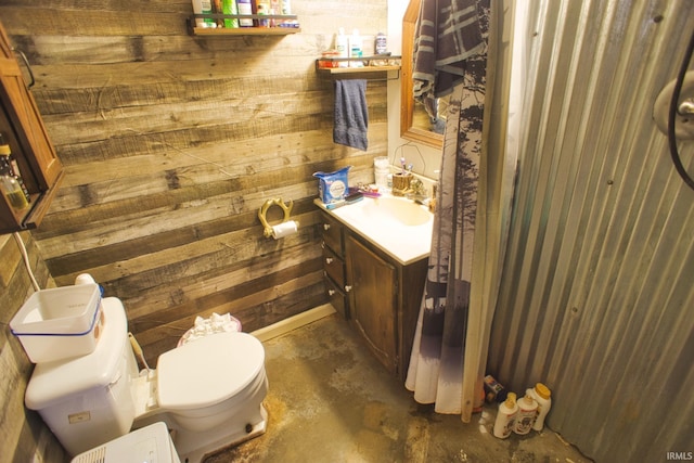 bathroom featuring toilet, vanity, concrete floors, and wood walls