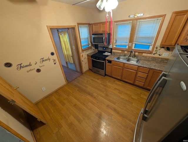 kitchen with stainless steel appliances, ceiling fan, light hardwood / wood-style floors, and sink