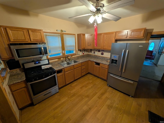 kitchen featuring sink, light hardwood / wood-style flooring, ceiling fan, dark stone countertops, and stainless steel appliances