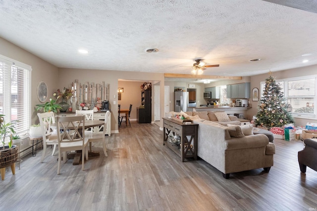 living room featuring a textured ceiling, light hardwood / wood-style flooring, ceiling fan, and a healthy amount of sunlight