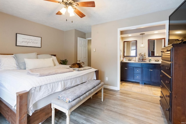 bedroom with connected bathroom, light hardwood / wood-style flooring, ceiling fan, and sink