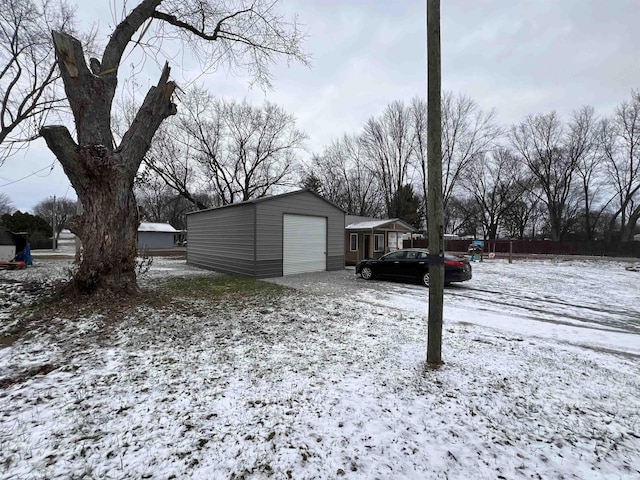 snowy yard featuring an outdoor structure and a garage