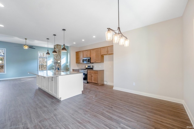 kitchen featuring a center island with sink, decorative light fixtures, dark wood-type flooring, and appliances with stainless steel finishes