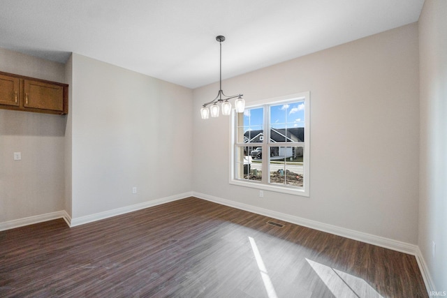 unfurnished dining area featuring dark hardwood / wood-style floors and an inviting chandelier