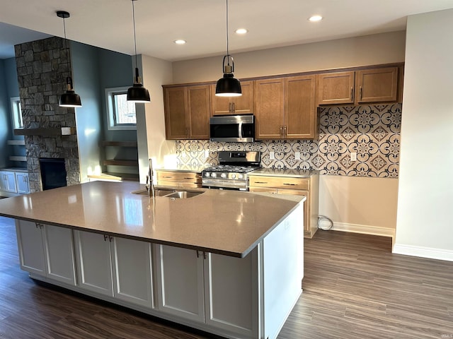 kitchen featuring a large island with sink, dark hardwood / wood-style flooring, stainless steel appliances, and hanging light fixtures