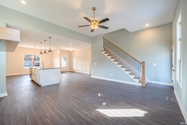 unfurnished living room featuring ceiling fan, sink, and dark hardwood / wood-style floors