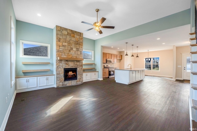 unfurnished living room featuring a fireplace, ceiling fan, dark wood-type flooring, and sink