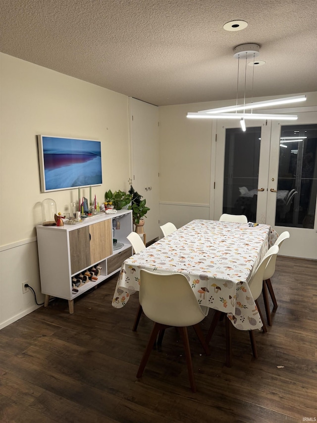 dining area featuring french doors, a textured ceiling, and dark hardwood / wood-style floors