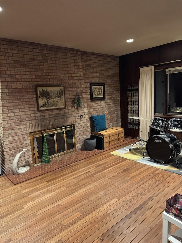 living room featuring light hardwood / wood-style flooring, brick wall, and a brick fireplace